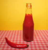 A chili pepper and a bottle of ketchup.