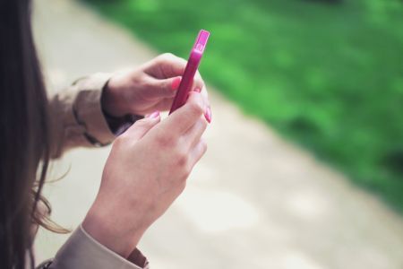 A woman looking at earned media on her phone.