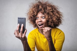A very excited person looking at a phone.