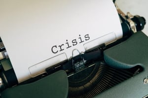 A typewriter with paper and the word “crisis” is written on it.