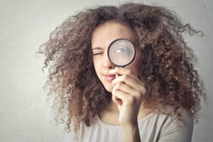 A woman discovering something with a magnifying glass.